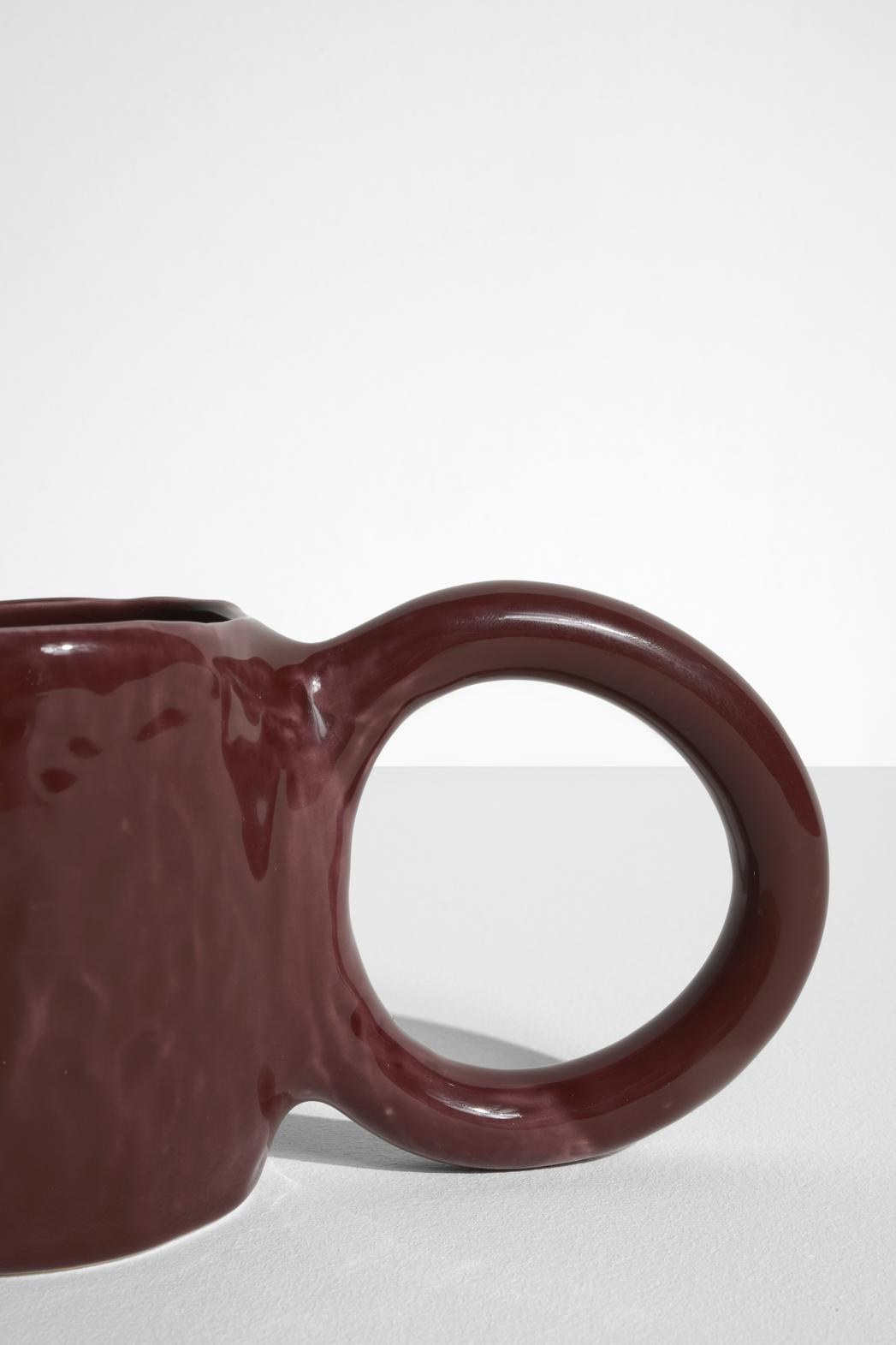 Keramiktasse Donut in Pistazie mit glasierter Oberfläche und donutförmigem Henkel, mittlere Grösse, handwerklicher Look, auf hellem Hintergrund.