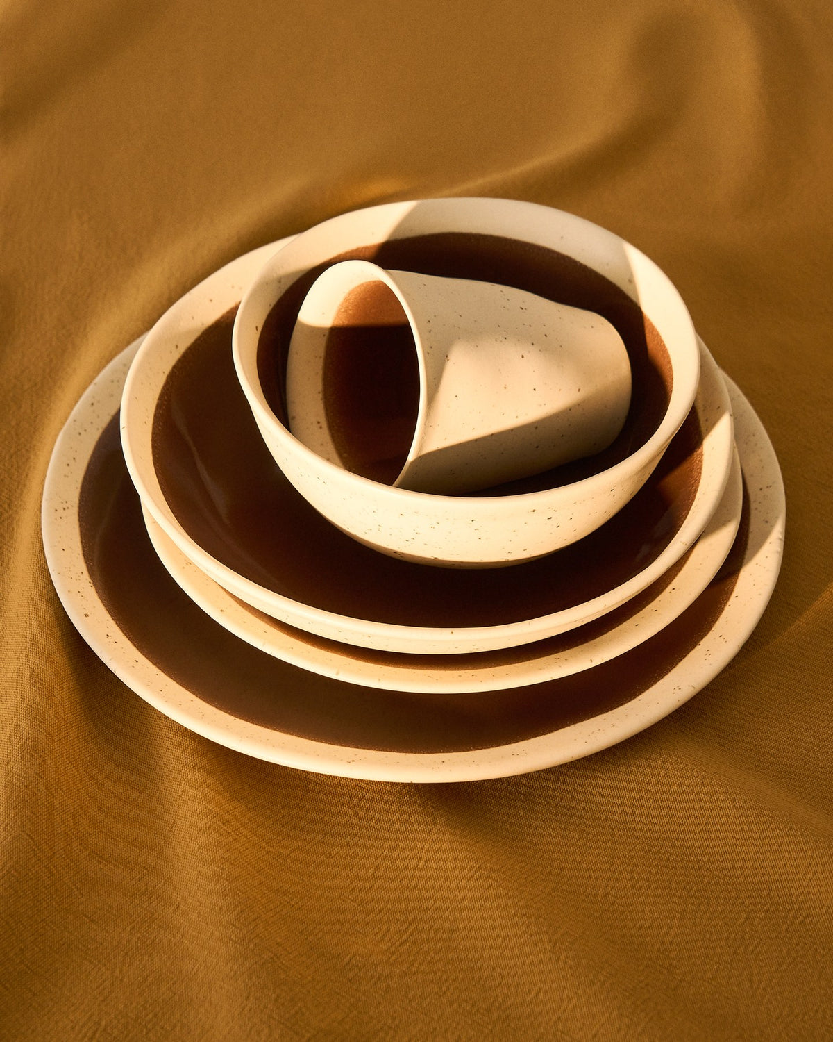 Flacher Teller aus Keramik in Beige mit braunem Boden, glänzende Oberfläche, runde Form, Durchmesser 27.5 cm, Höhe 3 cm.