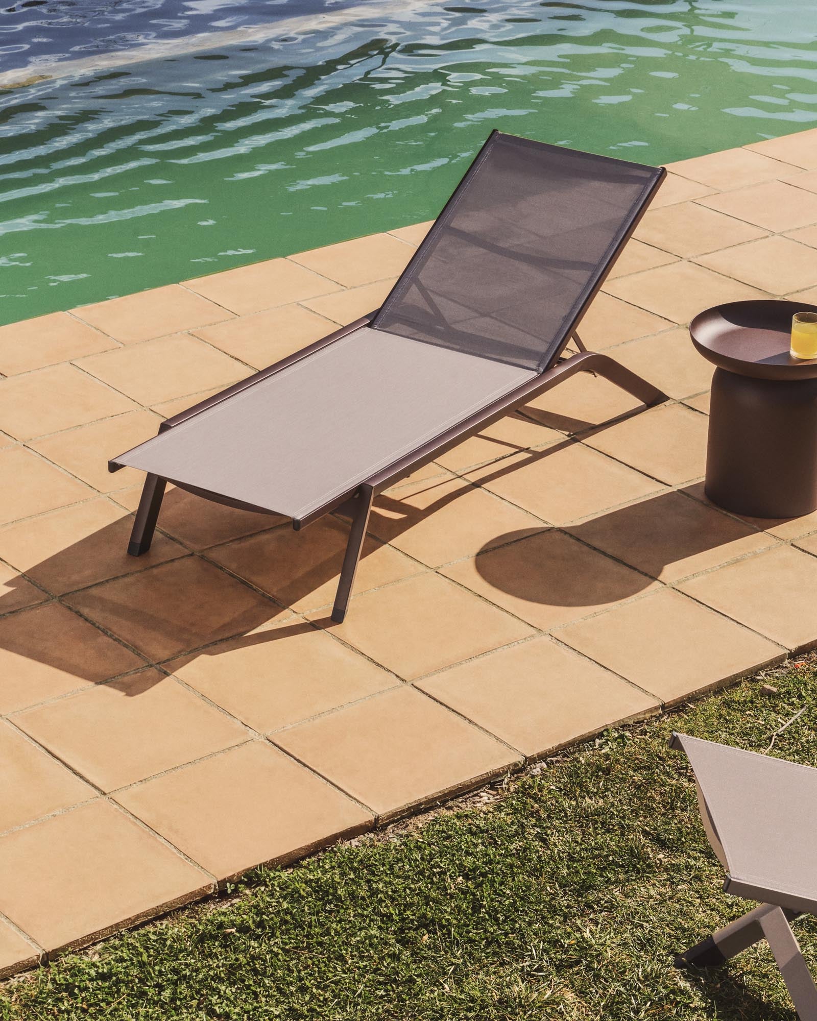 Elegante stapelbare Sonnenliege Capraia aus robustem braunem Aluminium und hellem Texteline, ideal für entspannte Stunden im Freien.