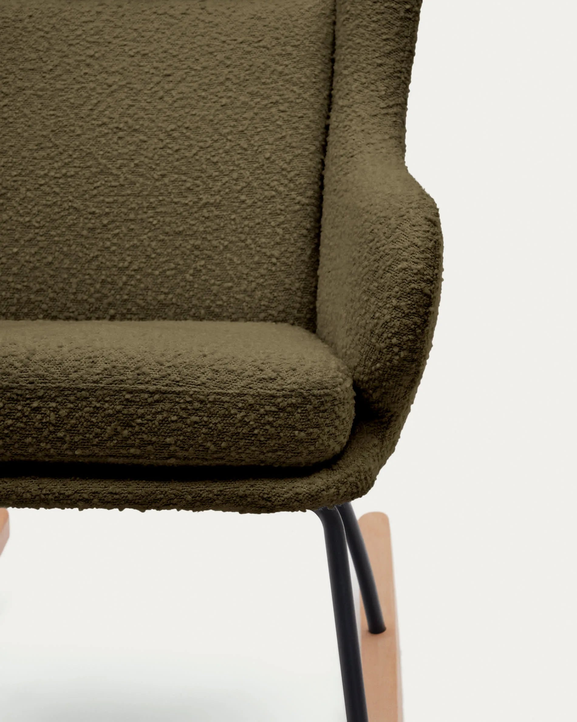 Eleganter Schaukelstuhl mit dunkelgrünem Bouclé, Stahl- und Buchenholzgestell, ideal für stilvolle Entspannung.