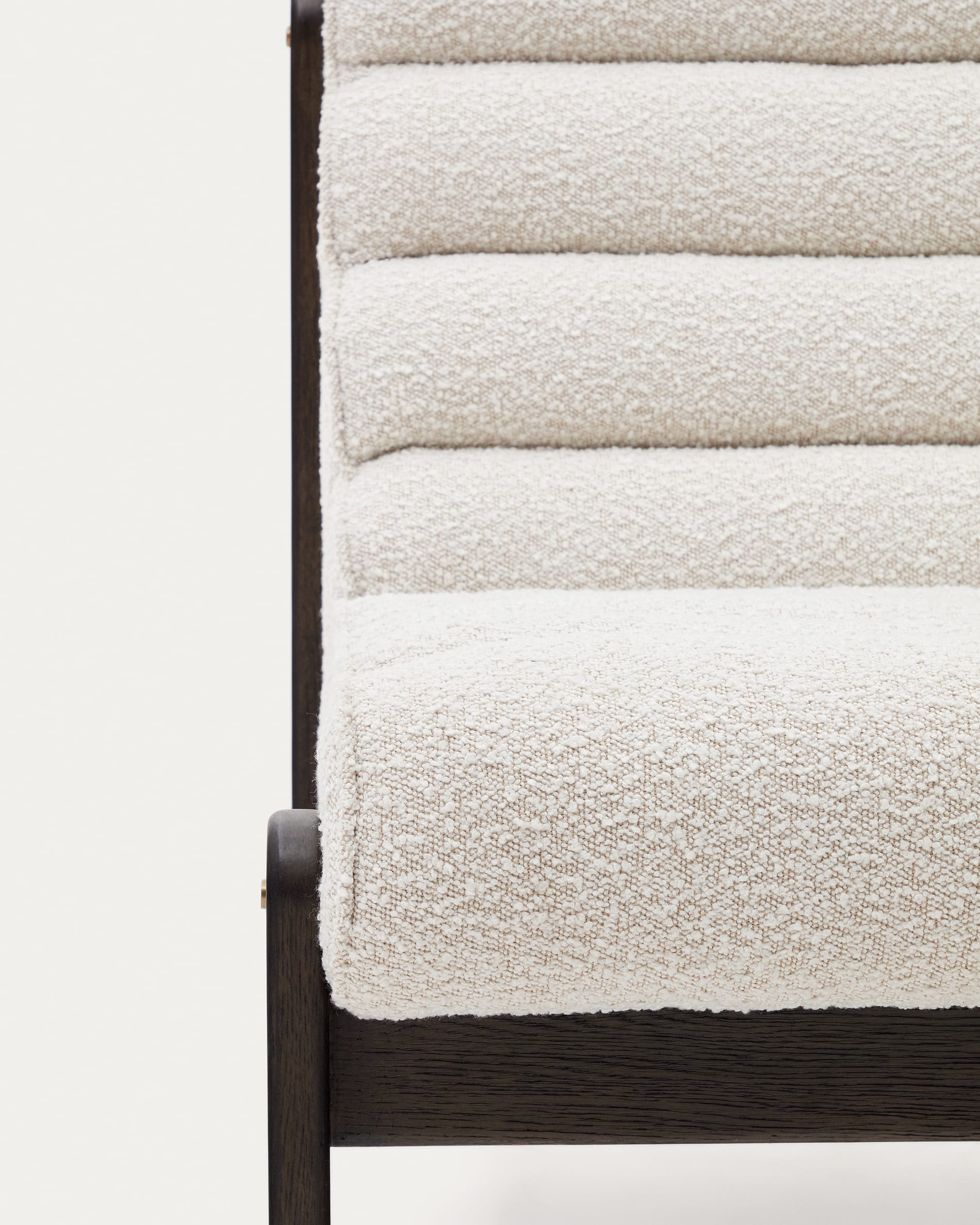 Der Sessel Magira besticht durch weißen Bouclé-Stoff und dunkles Eichenholz, perfekt für moderne und elegante Wohnräume.