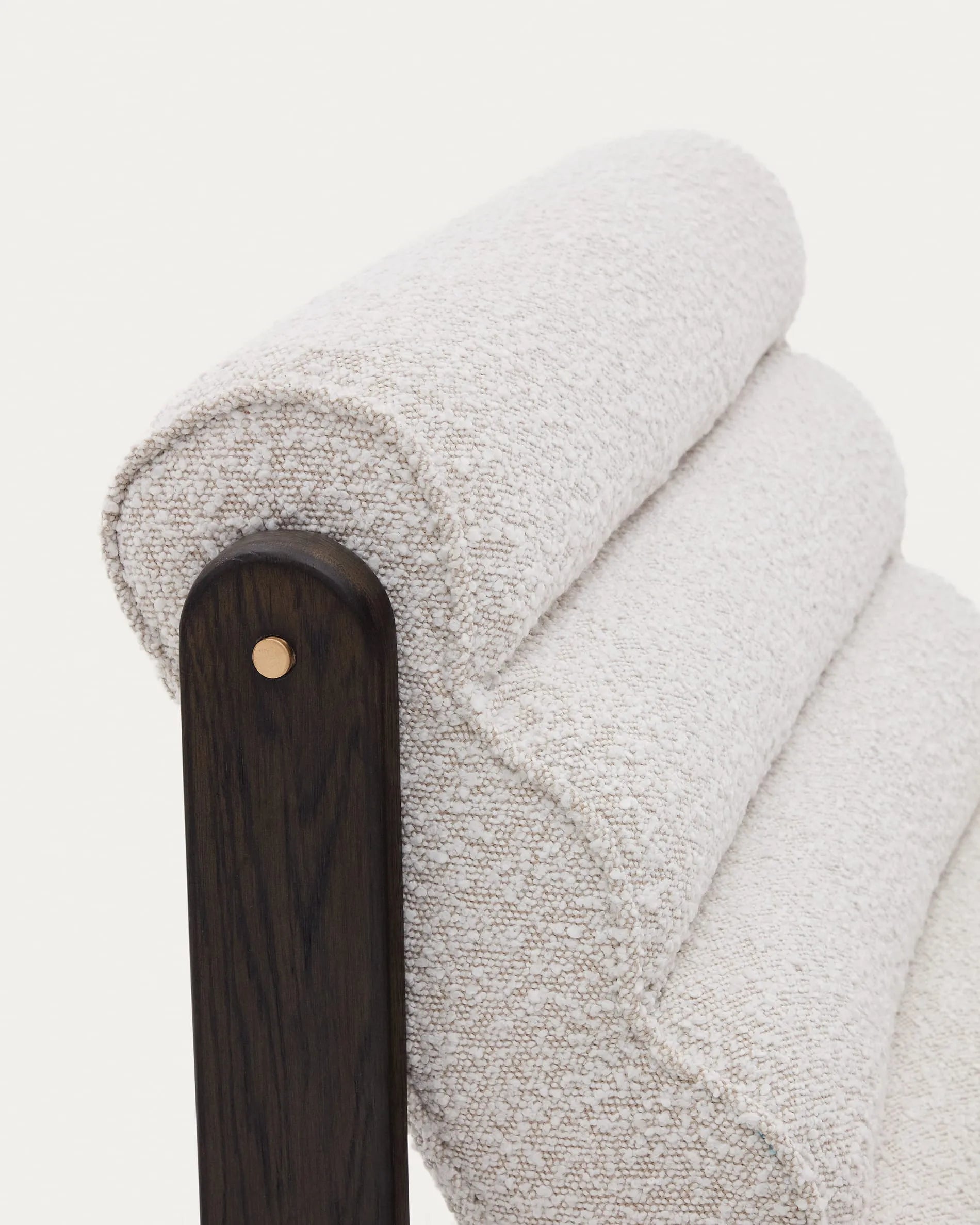 Der Sessel Magira aus weißem Bouclé und dunklem Eichenholz vereint Komfort und modernes Design für elegante Wohnräume.