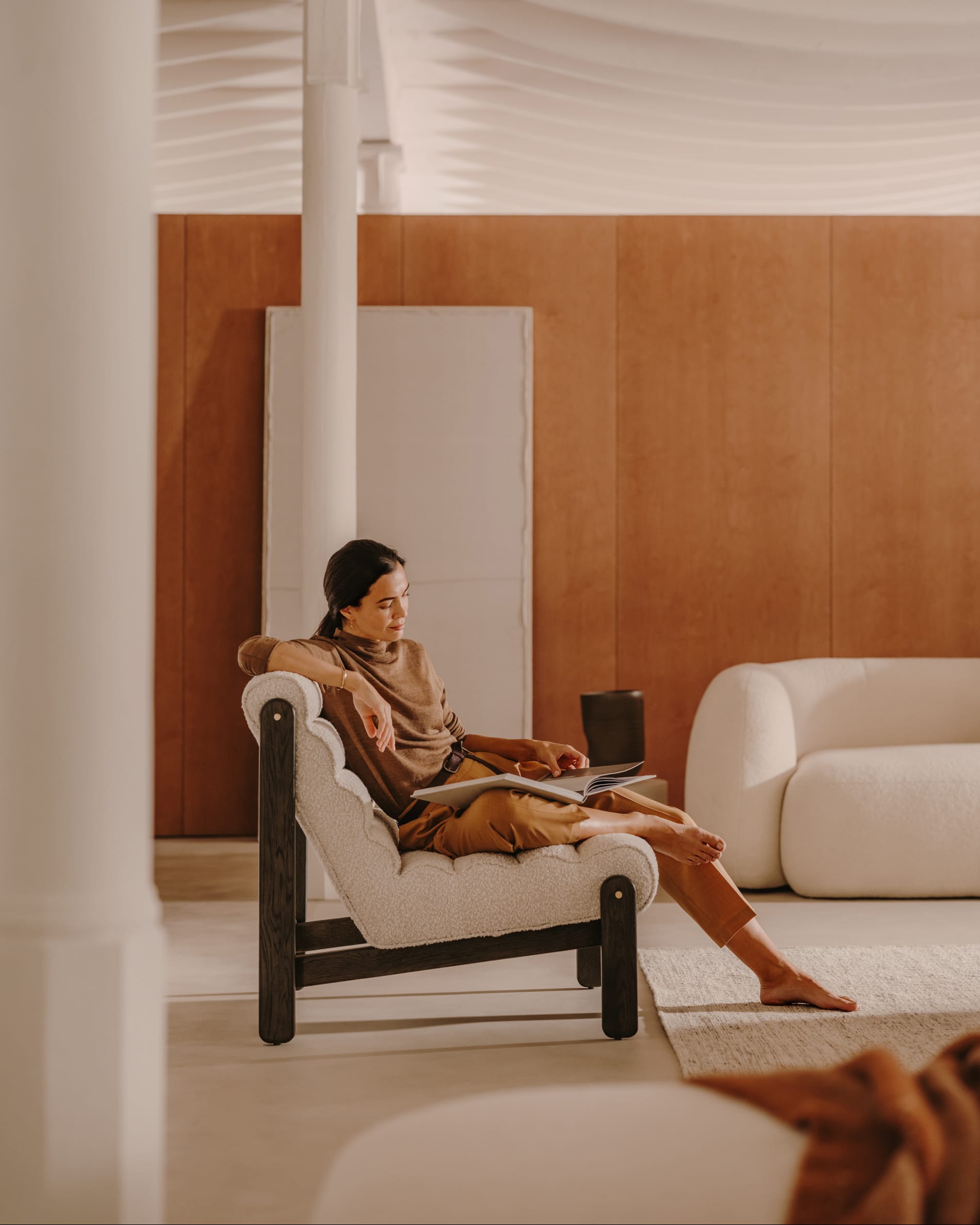 Eleganter Sessel Magira mit weißem Bouclé-Bezug und dunklem Eichenholz, ideal für stilvolle und moderne Wohnräume.