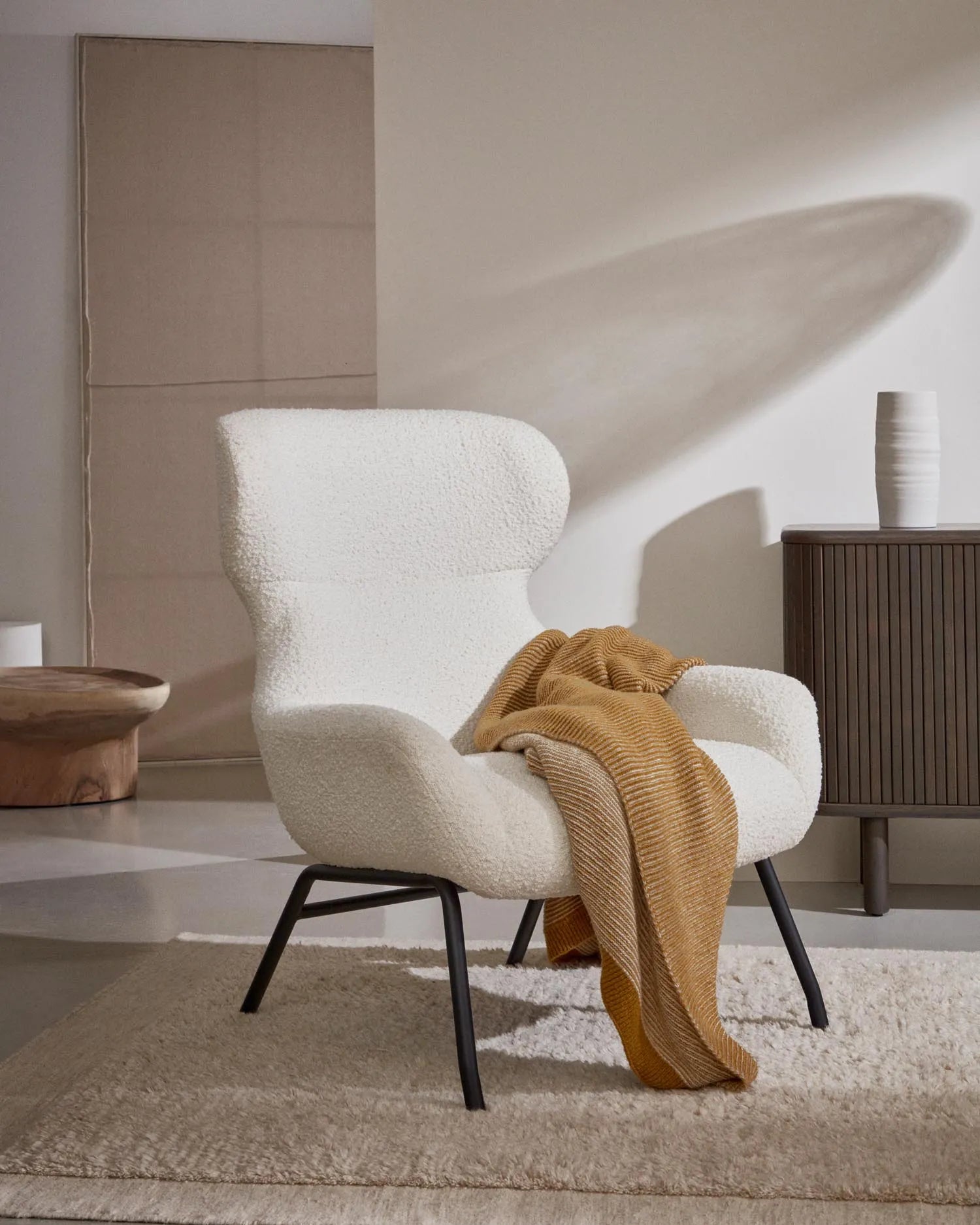 Eleganter Sessel aus weißem Bouclé mit schwarzen Stahlbeinen, FSC-zertifiziert, für stilvolle und nachhaltige Einrichtung.