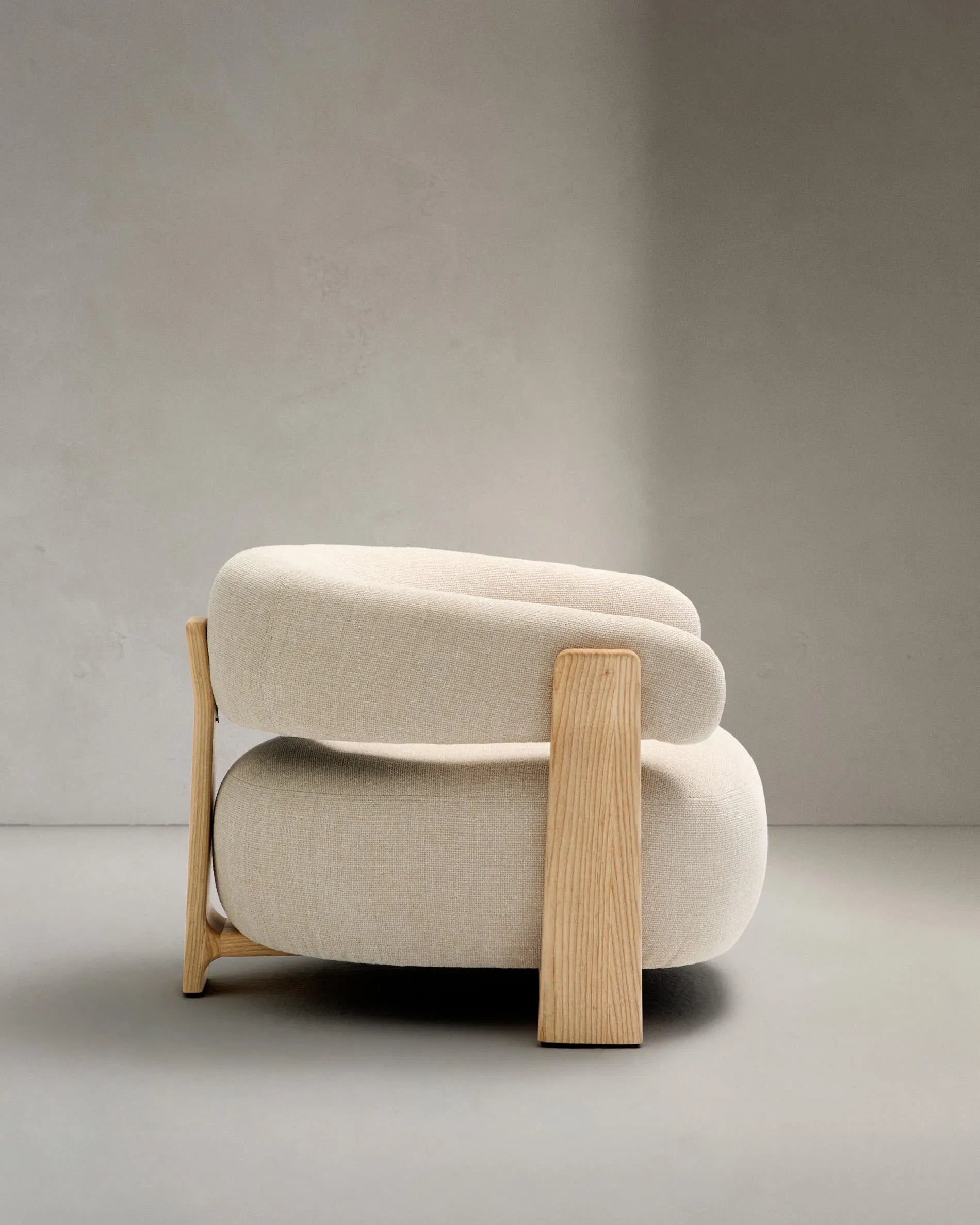 Ein eleganter Sessel mit beigefarbenem Chenille-Bezug und massiven Eschenholzbeinen, inspiriert von skandinavischem Design.
