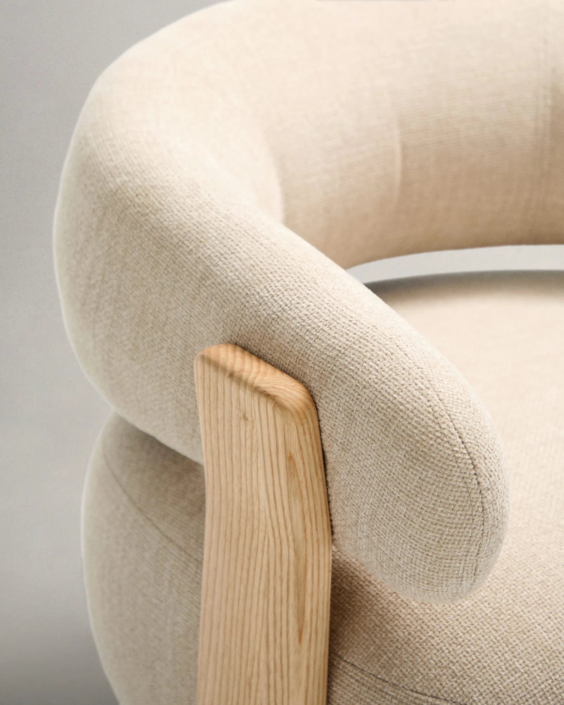 Ein eleganter Sessel mit beigefarbenem Chenille-Bezug und massiven Eschenholzbeinen, inspiriert von skandinavischem Design.
