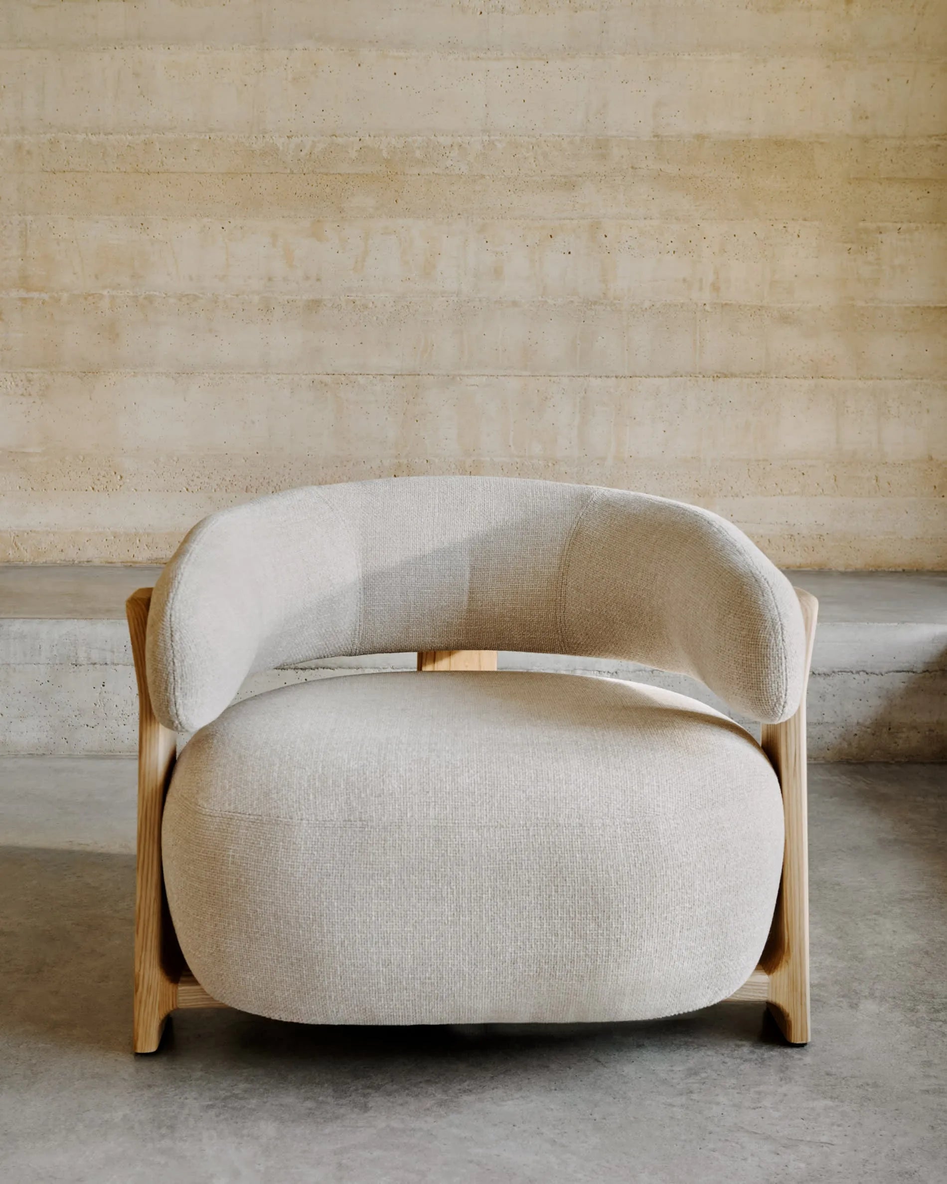 Ein eleganter Sessel mit beigefarbenem Chenille-Bezug und massiven Eschenholzbeinen, inspiriert von skandinavischem Design.