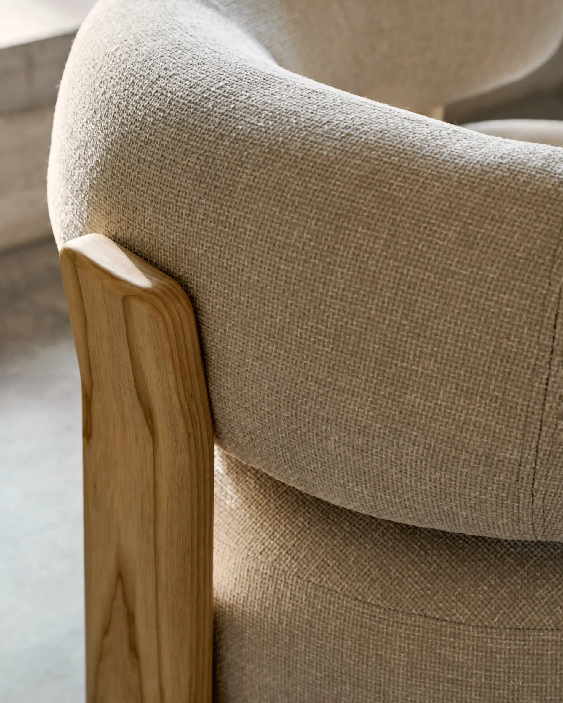 Ein eleganter Sessel mit beigefarbenem Chenille-Bezug und massiven Eschenholzbeinen, inspiriert von skandinavischem Design.