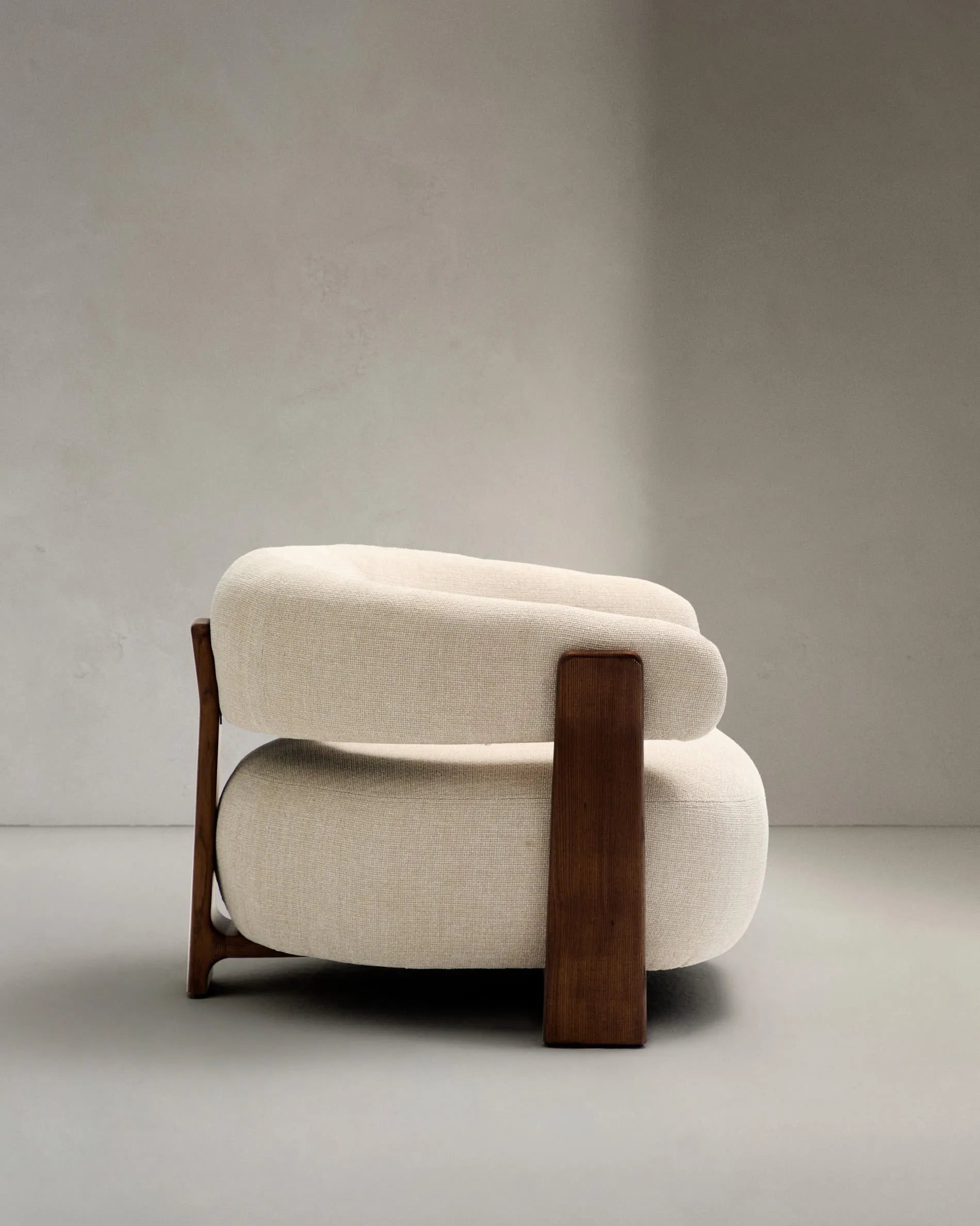 Moderner Sessel aus beiger Chenille, FSC-zertifizierte Eschenholzbeine mit Walnuss-Finish, stilvoll und umweltfreundlich.