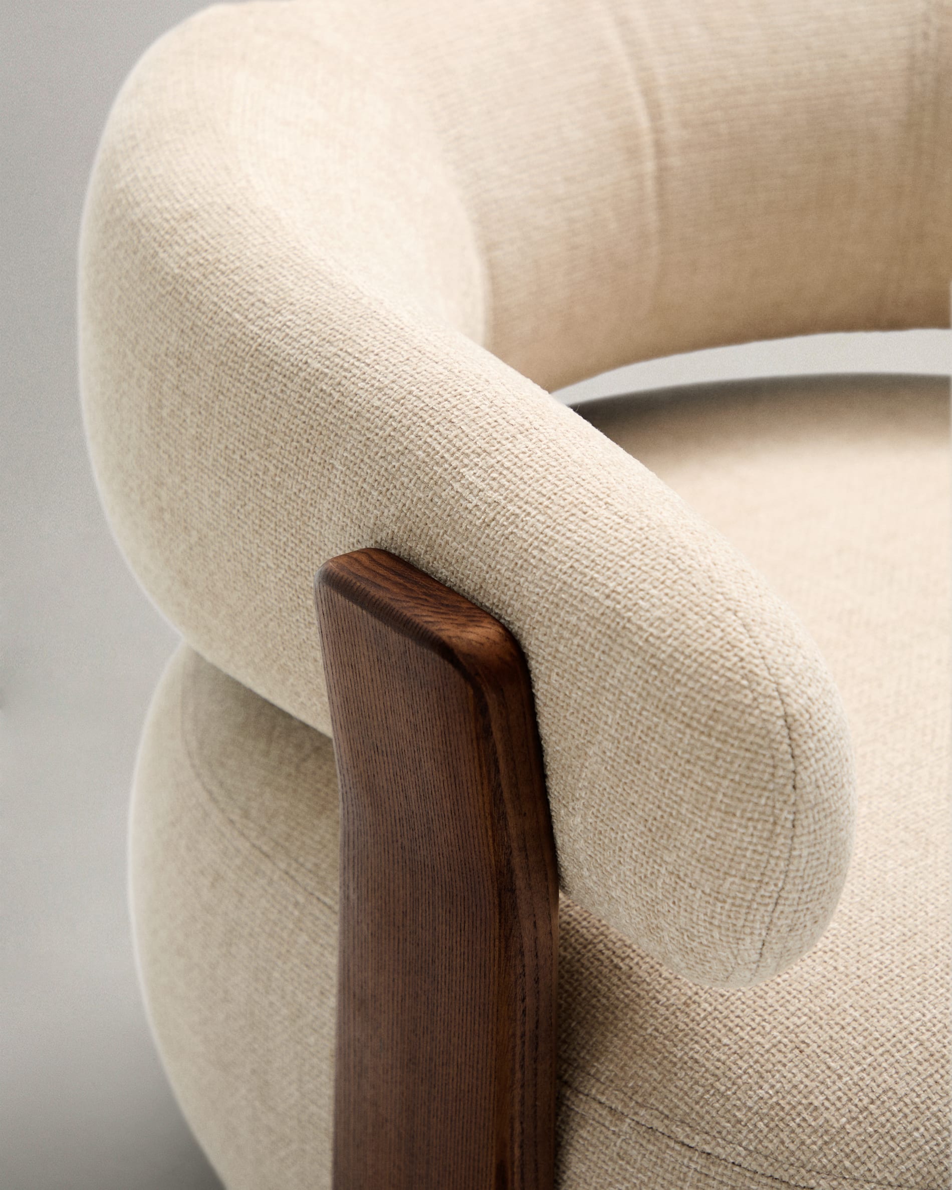 Moderner Sessel aus beiger Chenille, FSC-zertifizierte Eschenholzbeine mit Walnuss-Finish, stilvoll und umweltfreundlich.