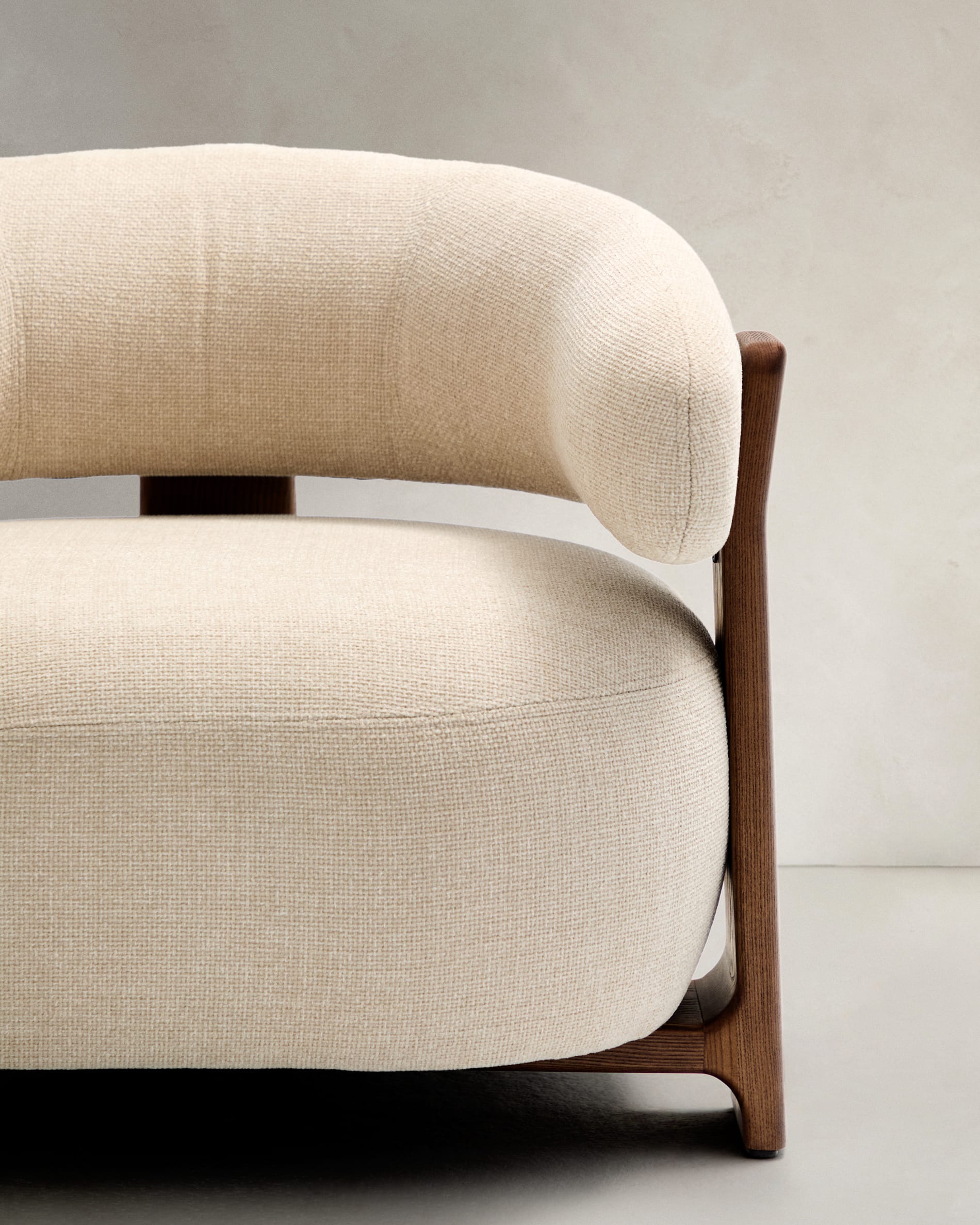 Eleganter Sessel aus beiger Chenille, Beine aus FSC-zertifiziertem Eschenholz mit Walnuss-Finish, modern und nachhaltig.