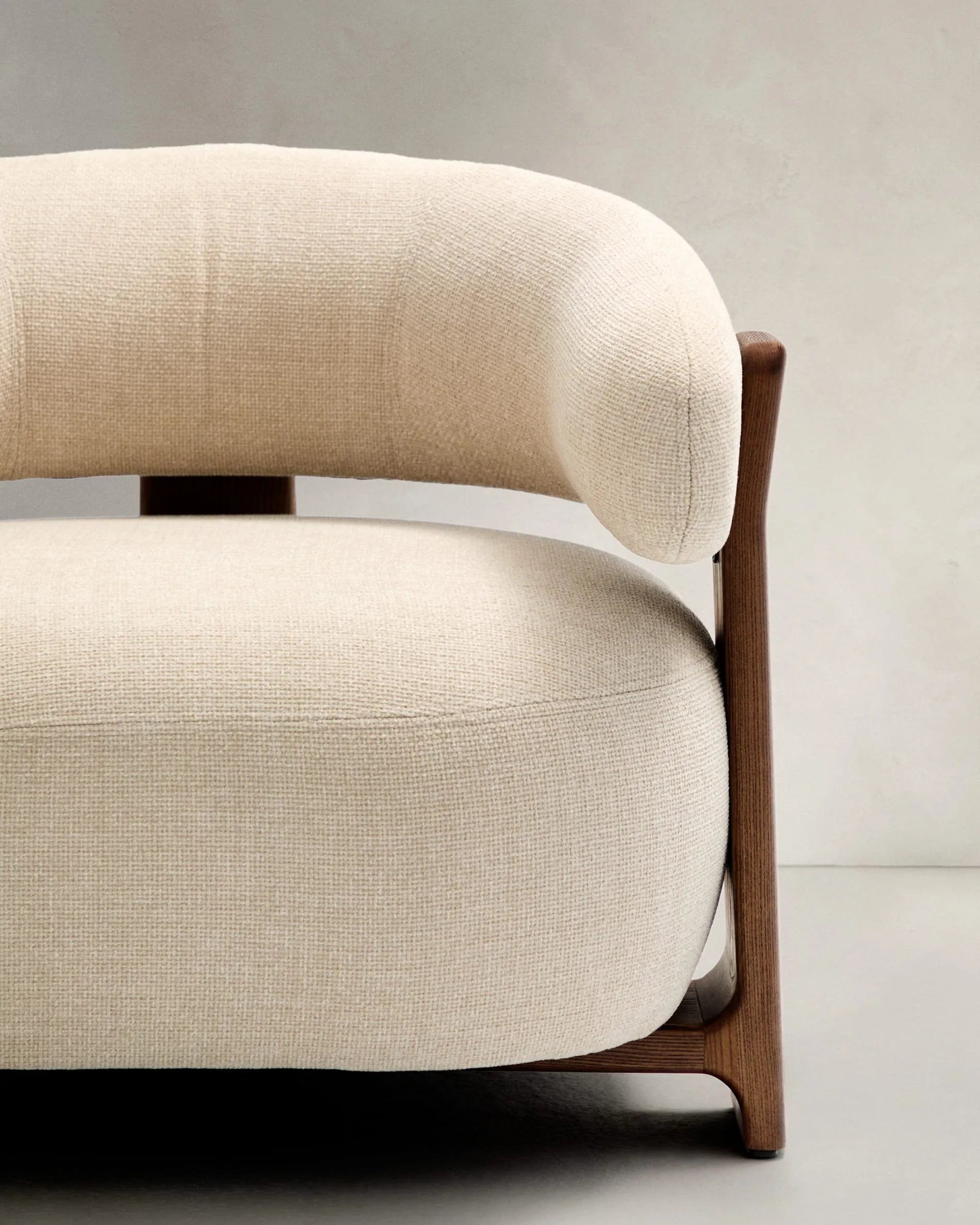 Eleganter Sessel aus beiger Chenille, Beine aus FSC-zertifiziertem Eschenholz mit Walnuss-Finish, modern und nachhaltig.