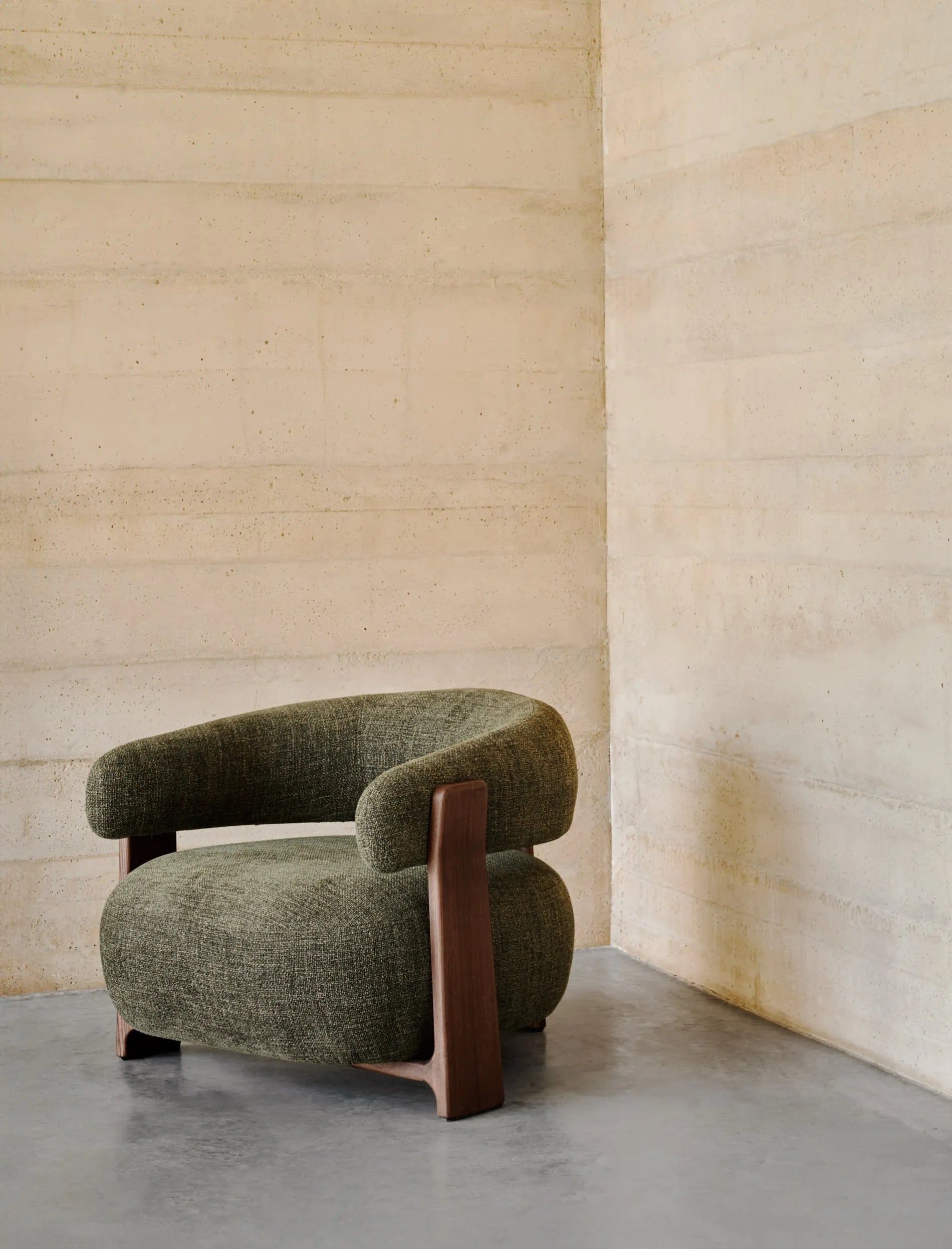 Moderner Sessel Granite mit grünem Chenille-Stoff und FSC-zertifizierten Eschenholzbeinen in Walnussoptik, komfortabel und umweltfreundlich.