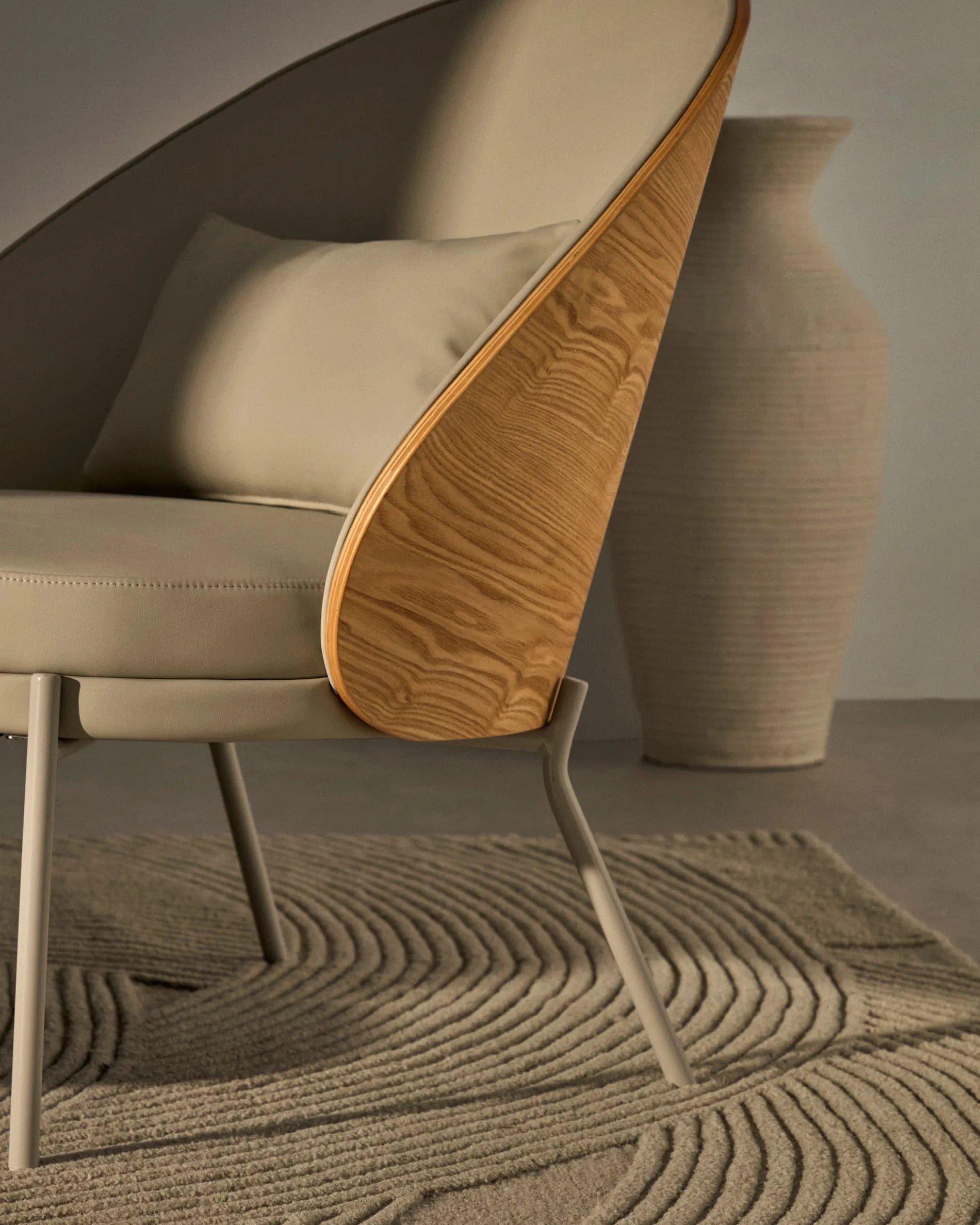 Eleganter Eamy Sessel mit beigem Kunstleder, Nussbaum-Eschenfurnier und Metallakzenten, ideal für stilvolle Räume.