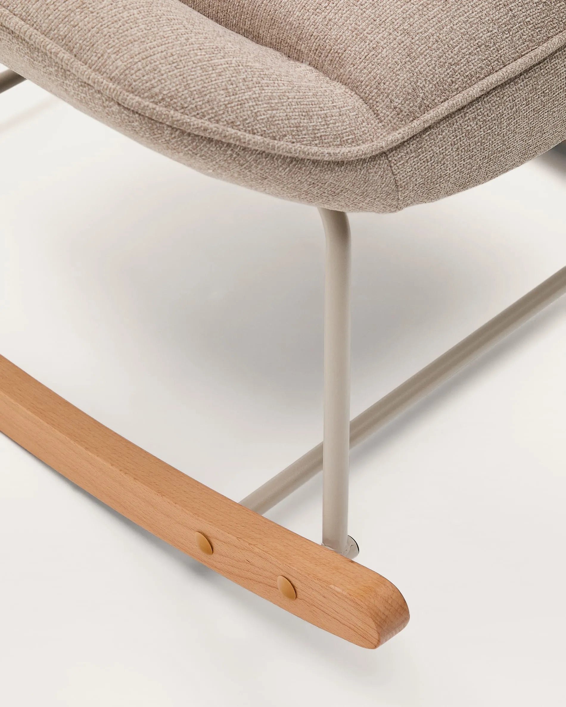 Der Schaukelstuhl Marlina vereint elegantes Design mit Komfort: Beigefarbener Chenille-Stoff trifft auf mattgraues Metall.