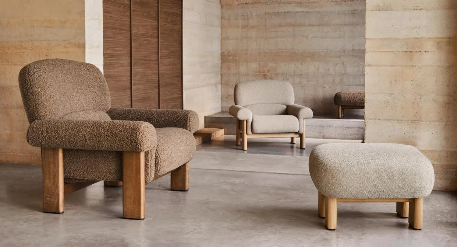 Der Sessel Nema kombiniert taupefarbenes Bouclé mit massivem Eschenholz, bietet luxuriösen Komfort und zeitlose Eleganz.