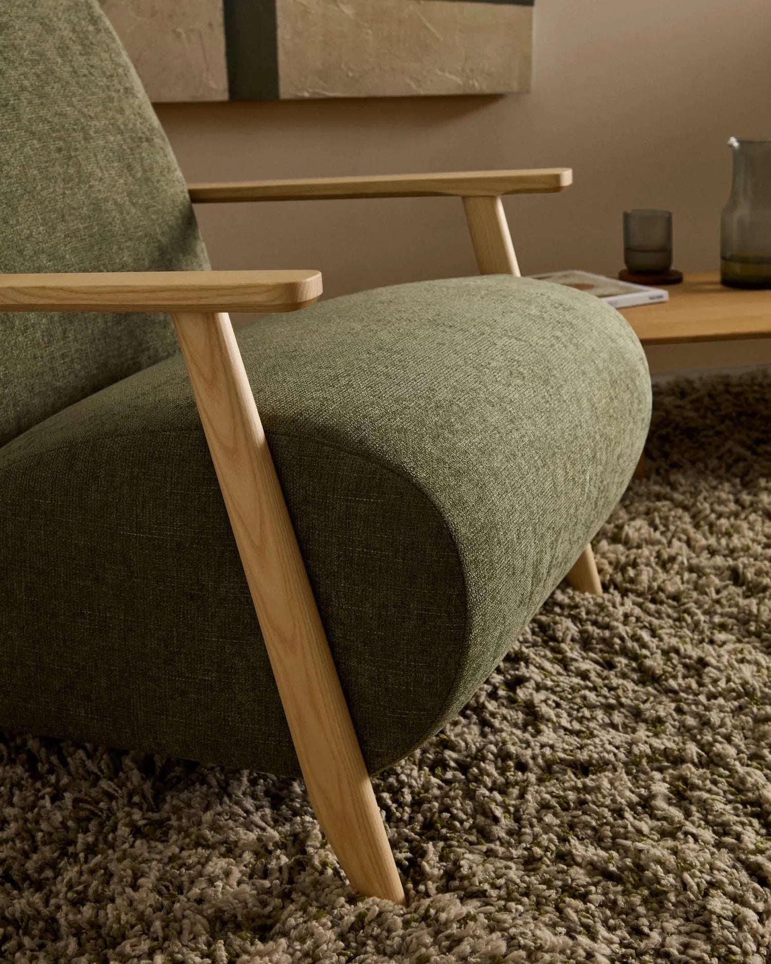Eleganter Sessel aus grünem Chenille und Eschenholz, FSC-zertifiziert, bietet Komfort und Stil für jeden Raum.