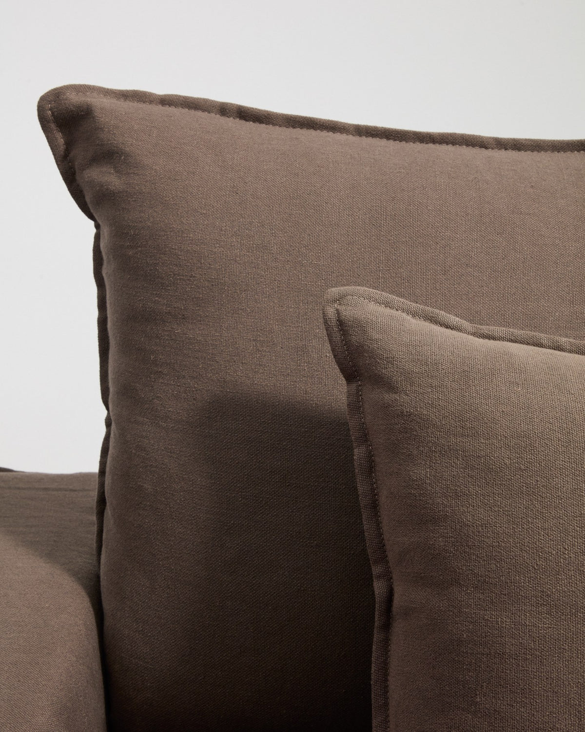Sessel Anarela mit abnehmbarem Leinenbezug in Taupe, schwarzen Kunststoffbeinen und gepolsterter Sitzfläche, Frontalansicht.