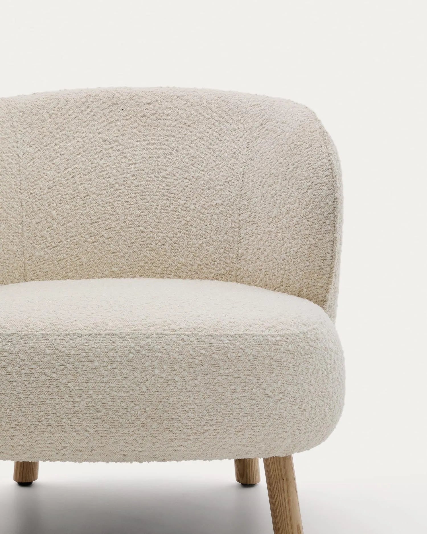 Eleganter Sessel mit weißem Schaffellbezug und stabilen Buchenholzbeinen, ideal für stilvolle, kompakte Räume.