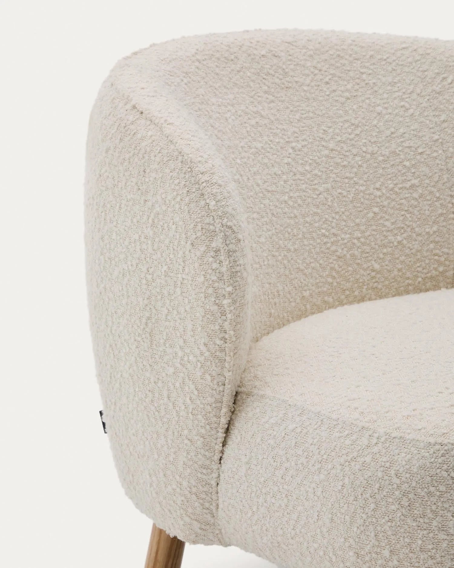 Eleganter Sessel mit weißem Schaffellbezug und stabilen Buchenholzbeinen, ideal für stilvolle, kompakte Räume.