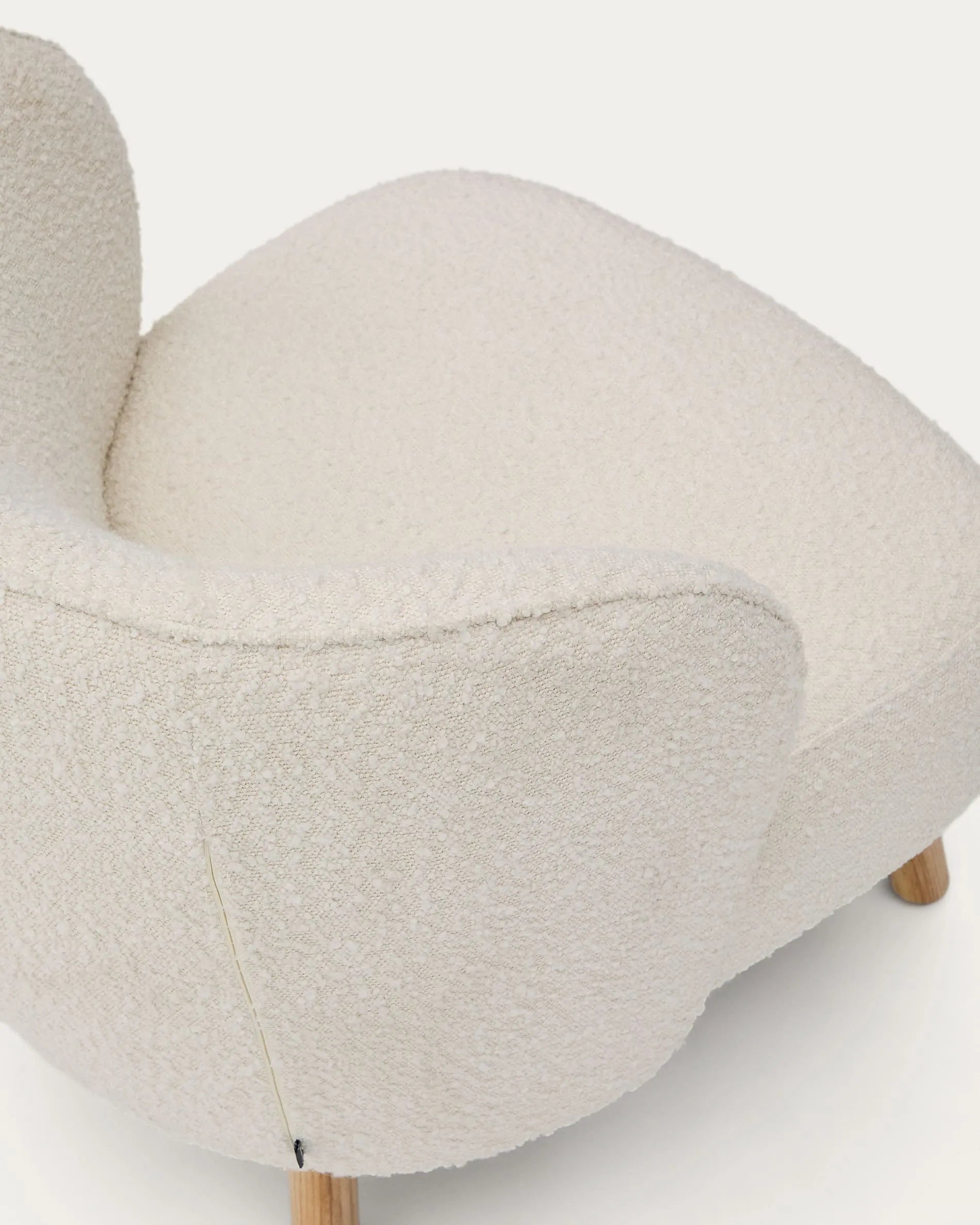 Eleganter Sessel mit weißem Schaffellbezug und stabilen Buchenholzbeinen, ideal für stilvolle, kompakte Räume.