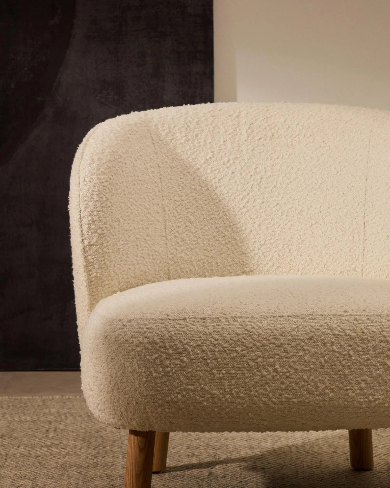 Eleganter Sessel mit weißem Schaffellbezug und stabilen Buchenholzbeinen, ideal für stilvolle, kompakte Räume.