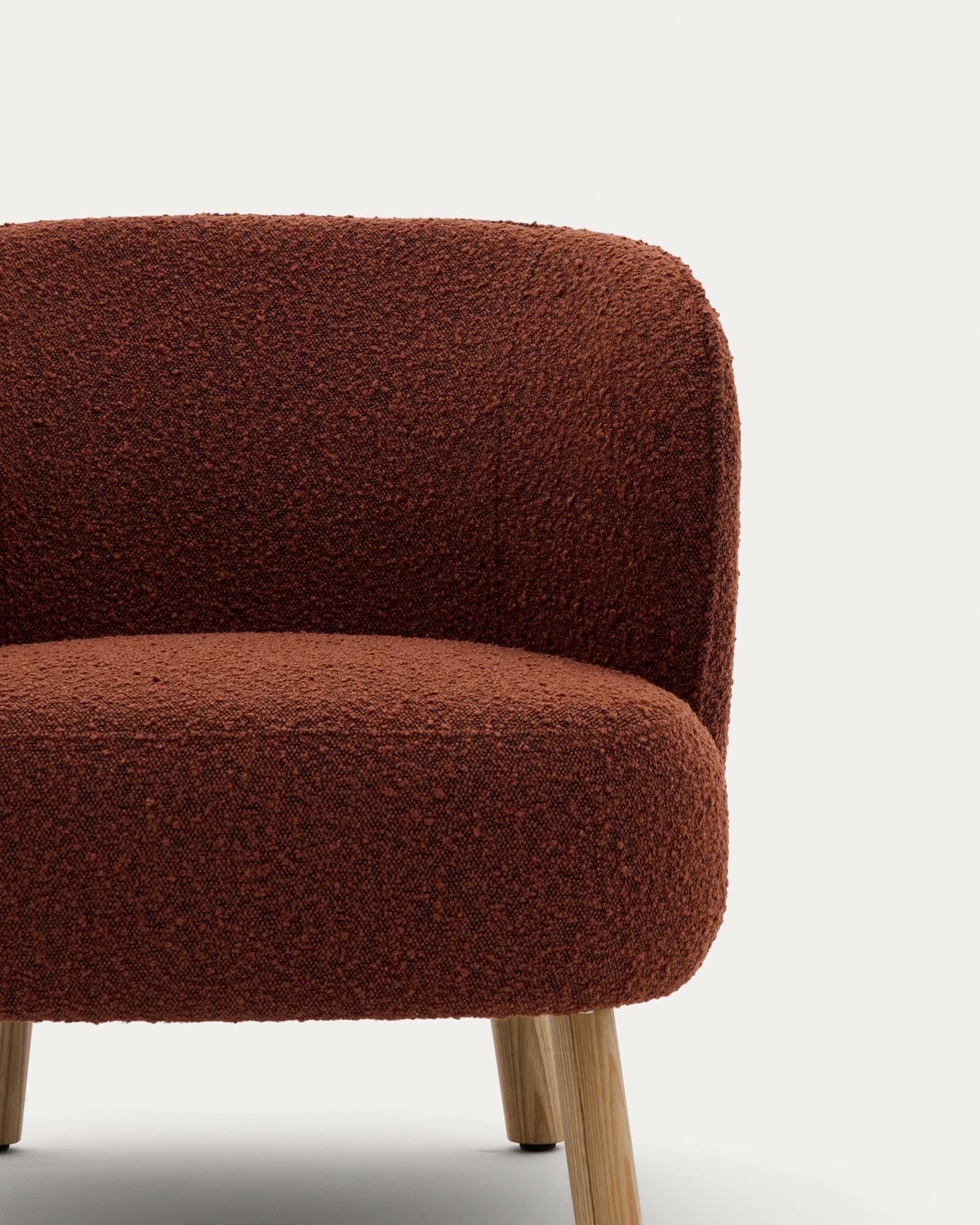 Sessel Ulit: Terrakottafarbenes Schaffell, Beine aus massivem Buchenholz, natürliches Finish, ideal für modernes Wohndesign.