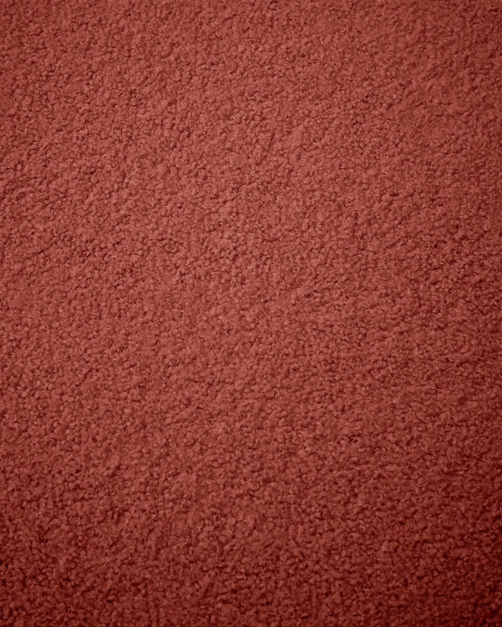 Der Kaeli Fußhocker in Terrakotta vereint Stil und Komfort mit recyceltem Bouclé-Bezug, ideal für jeden Wohnraum.