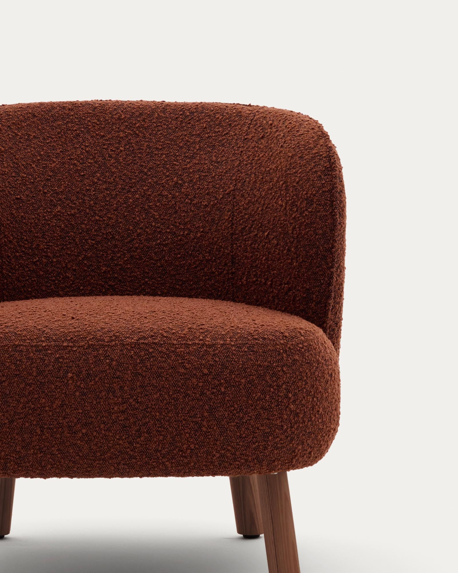 Eleganter Sessel Ulit in warmem Terrakotta-Look, gefertigt aus weichem Lammfellimitat und stabilen Eschenholzbeinen mit Nussbaum-Finish.