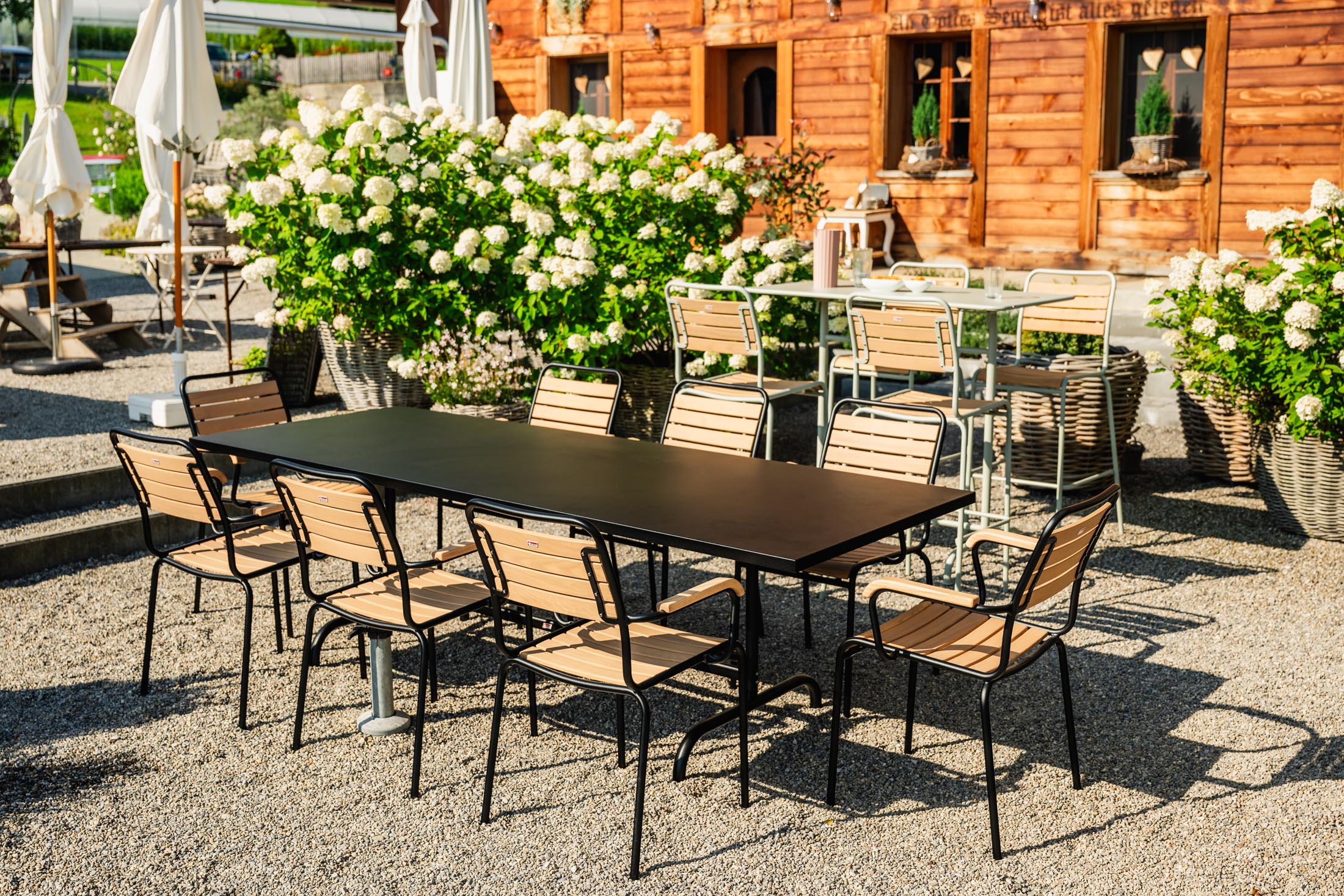 Eleganter Rigi Holzlatten-Gartenstuhl mit Armlehne aus robustem Eschenholz, Schweizer Qualität, wetterfest, pflegeleicht und nachhaltiges Design.