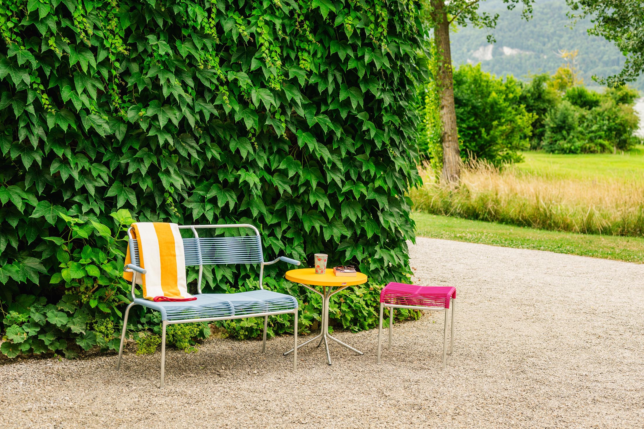 Elegante 2er Gartenbank mit Armlehne aus wetterfestem Metall, nachhaltigem Spaghetti-Design und Swiss Made Qualität – perfekt für Ihren Außenbereich.