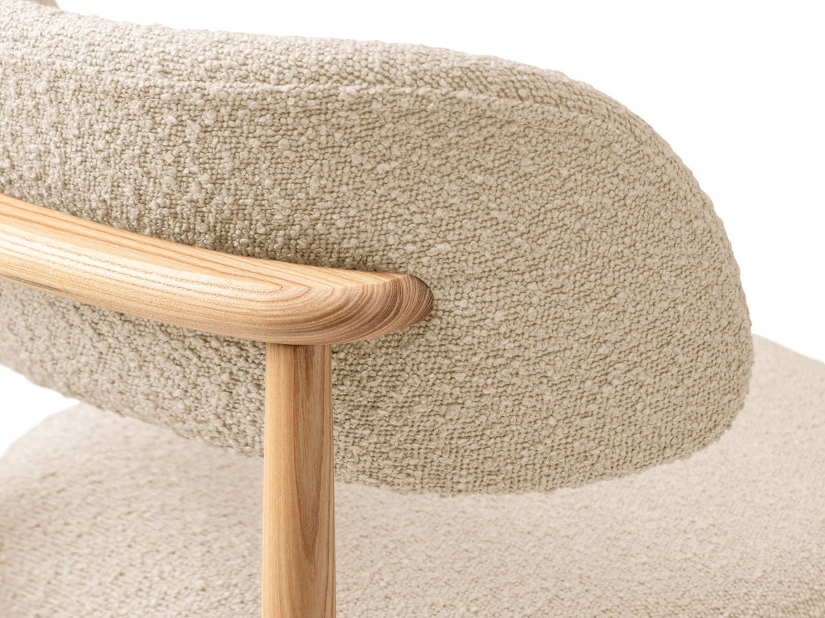 Zwei Boucle-Stühle Evan in Beige mit Buchenholz-Beinen, strukturiertem Bouclé-Bezug und gepolsterter Sitzfläche vor neutralem Hintergrund.
