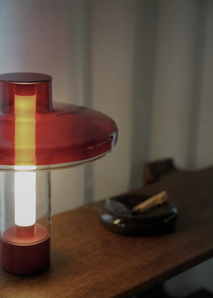 Moderne Nevo NVO01 Tischleuchte von Tamo, die durch ihr geschwungenes Design und warmes Licht eine einladende Atmosphäre schafft.