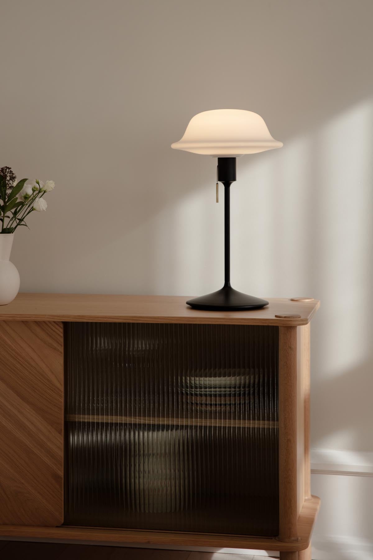 Elegante Butler Tisch- und Stehleuchte von Umage, die mit ihrem zeitlosen Design und warmem Licht eine einladende Atmosphäre schafft.