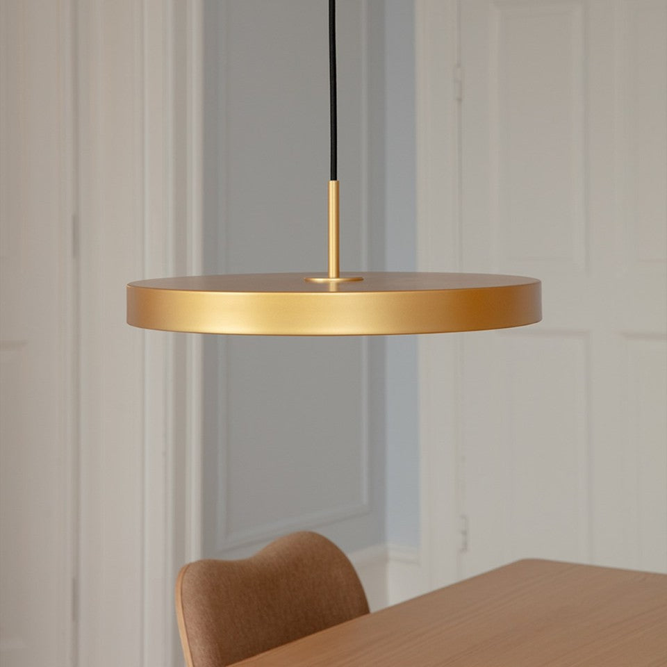 Elegante Asteria Plus Medium Pendellampe in Messing, ideal für stilvolle Innenräume, präsentiert in einem modernen Ambiente.