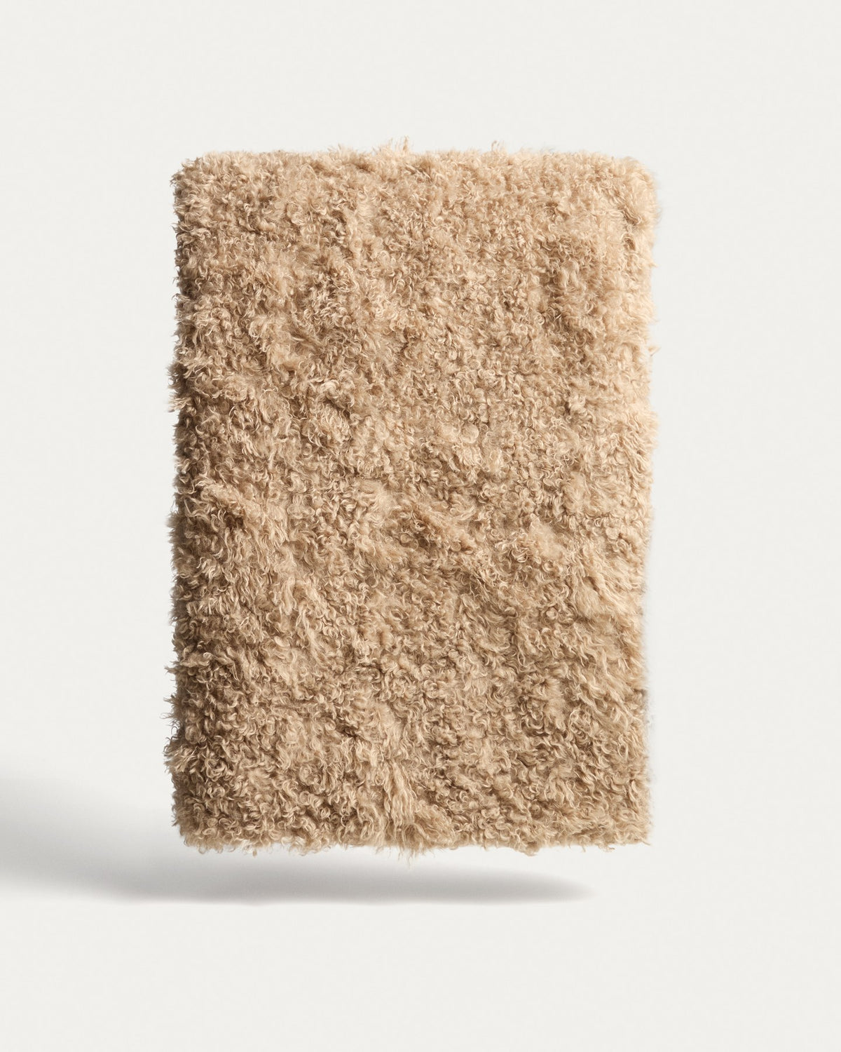 Beige Wolldecke aus Kunstfell mit lockiger Struktur, Grösse 140 x 200 cm, gefaltet dargestellt mit beiliegendem Tragegurt.