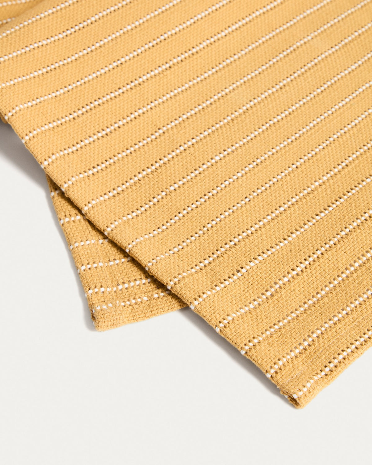 Foto des Tischläufers Noria aus Baumwolle mit Jacquard-Muster in Senfgelb, rechteckige Form, Masse 50 x 150 cm.