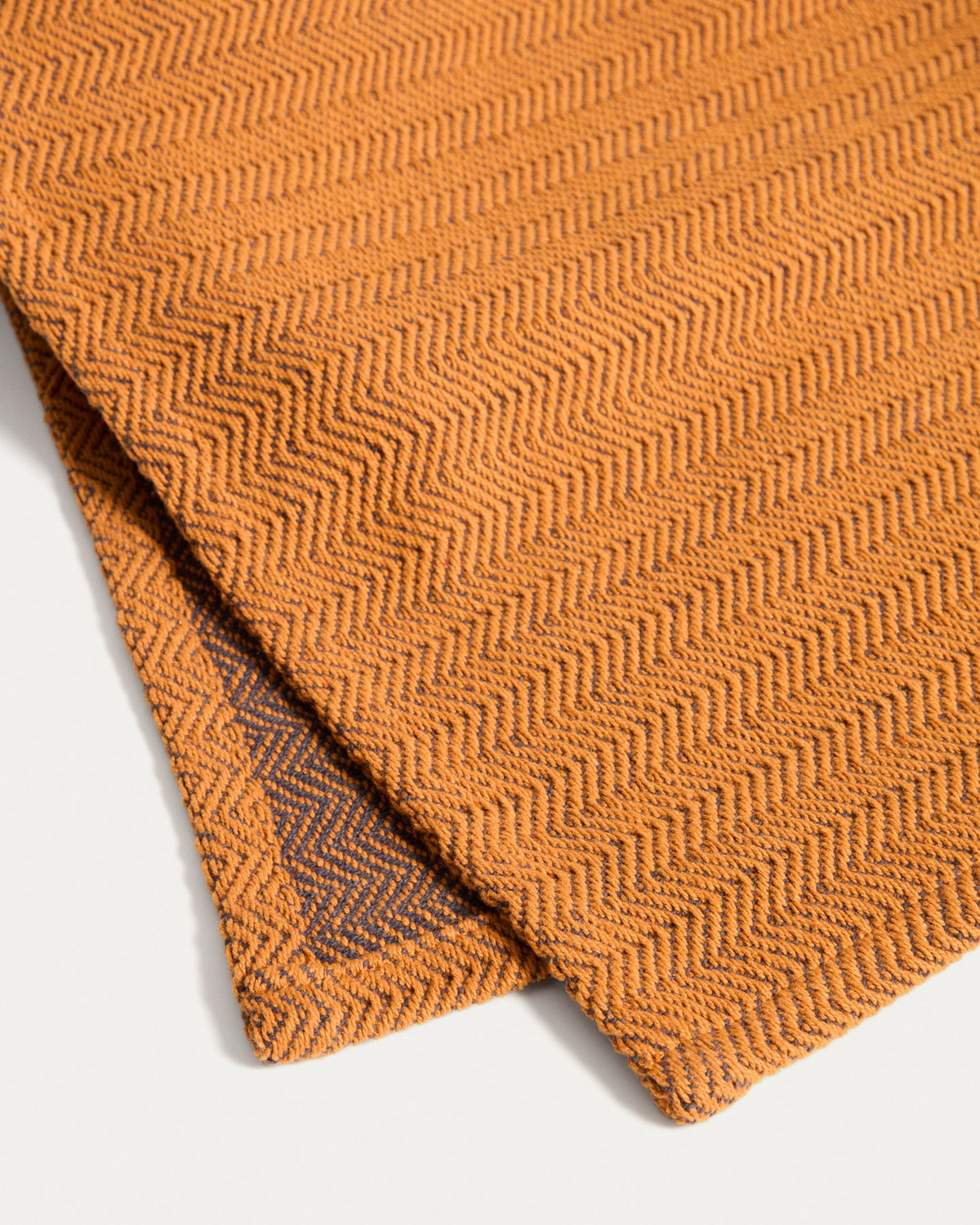 Tischläufer Tieva aus Baumwolle mit eingewebtem Jacquard-Muster in Senfgelb-Orange, rechteckige Form, 50 x 150 cm, auf einem Tisch drapiert.