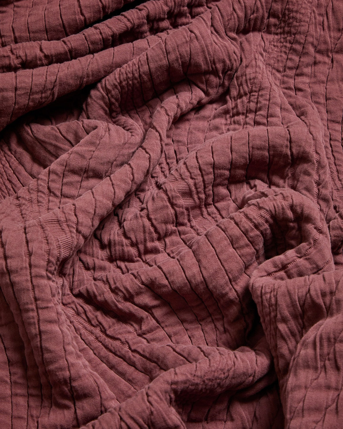 Weinrote Tagesdecke Sarula aus 100% Baumwolle mit Jacquard-Wellenmuster, ausgebreitet auf einem Bett, Grösse 240 x 260 cm.