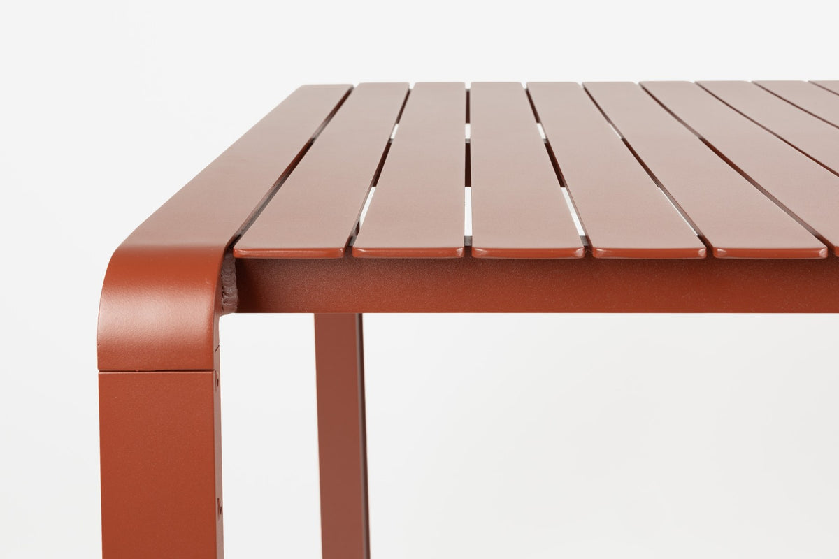 Roter Gartentisch Vondel von Zuiver aus pulverbeschichtetem Aluminium mit rechteckiger Tischplatte und schlanken Beinen im Freien.