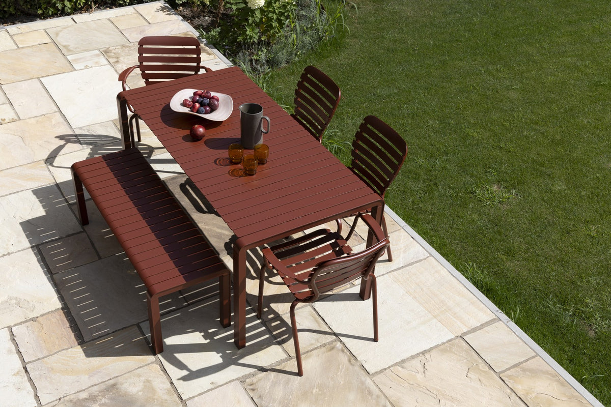 Roter Gartentisch Vondel von Zuiver aus pulverbeschichtetem Aluminium mit rechteckiger Tischplatte und schlanken Beinen im Freien.